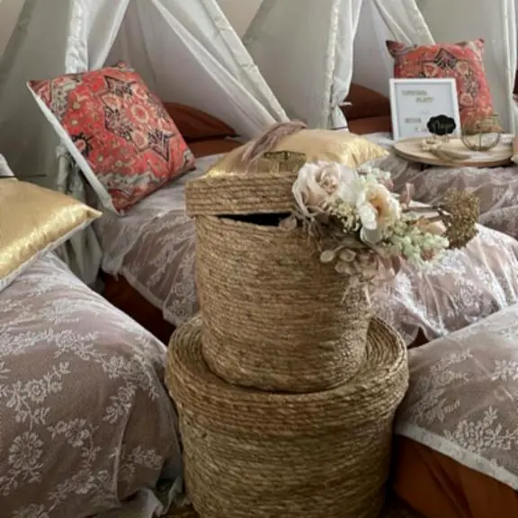 Rieten mand met droogbloemen tussen de boho bedden