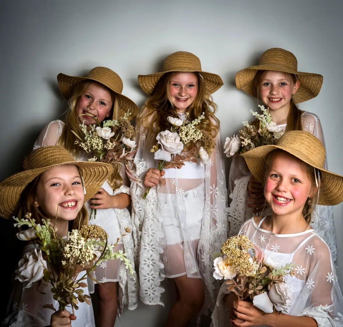 Meiden in kanten jurkjes met boeketjes droogbloemen