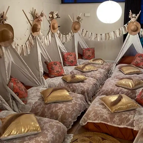 Lange rij boho tipi’s met kanten spreien en gouden kussens