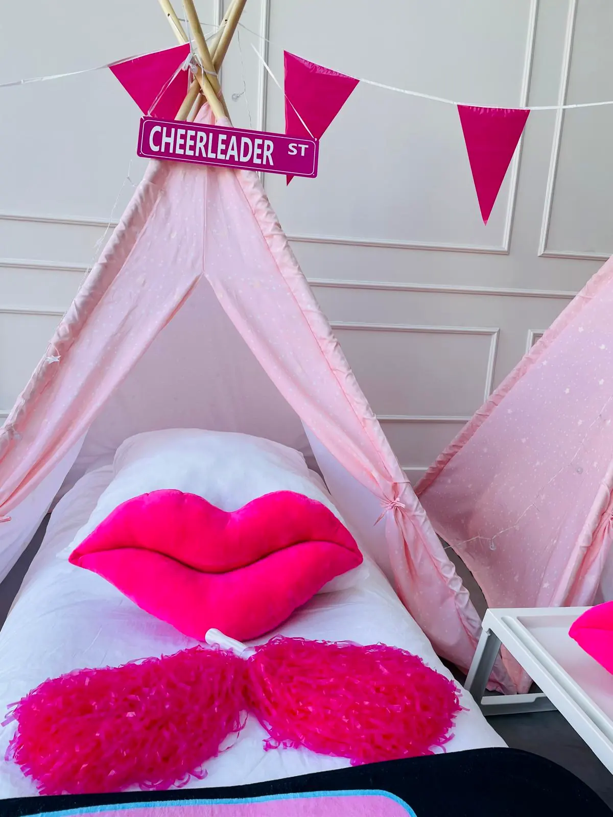 Roze lippenkussen en pompons op het bed in de cheerleader tipi