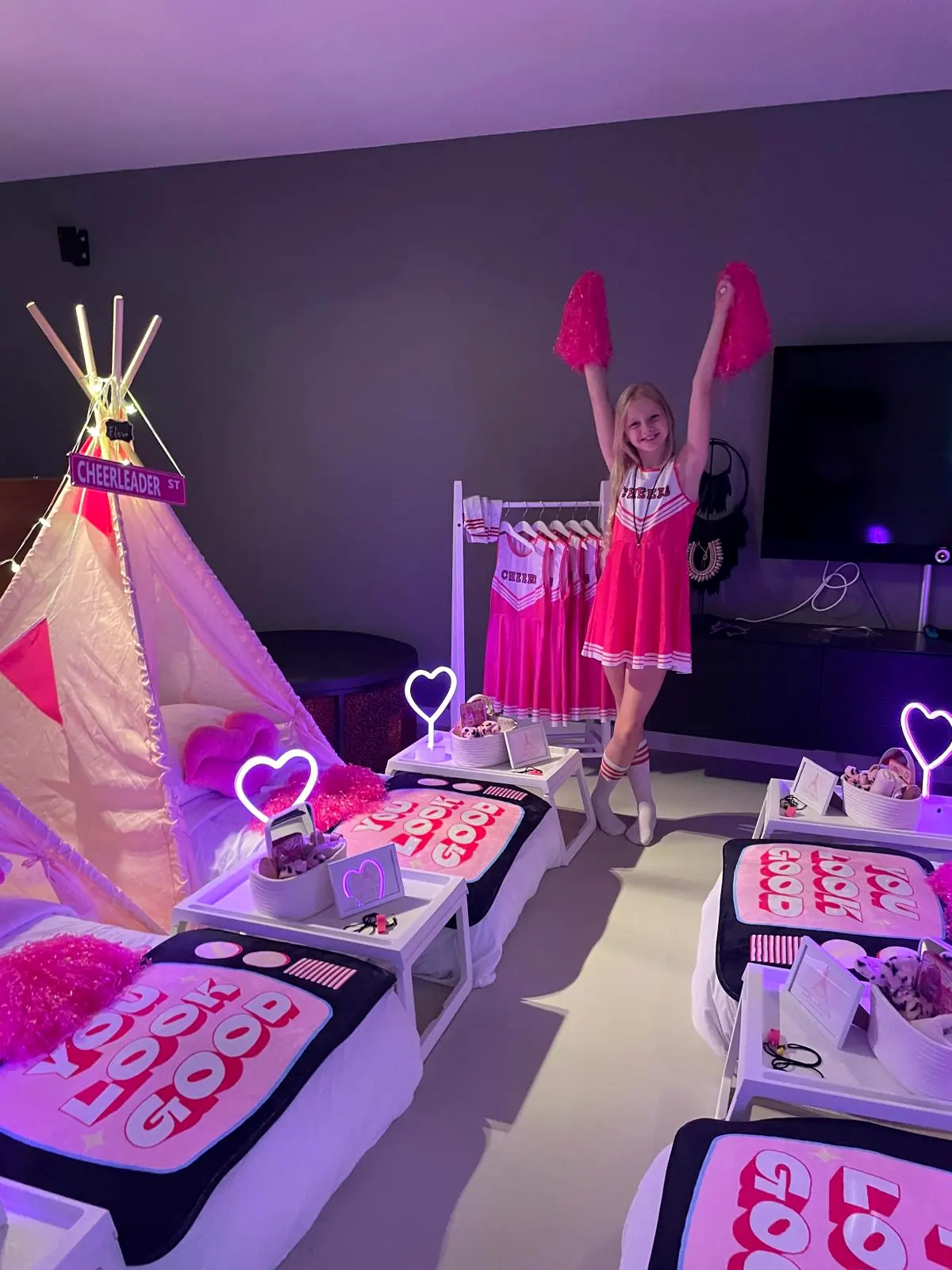 Meisje juicht met pompons in de lucht tussen de cheerleader tipi’s