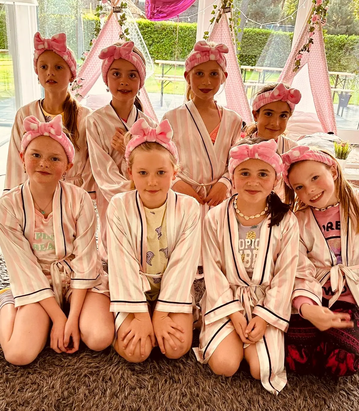 Meiden in witte badjassen met roze haarbanden bij het girlpower feestje