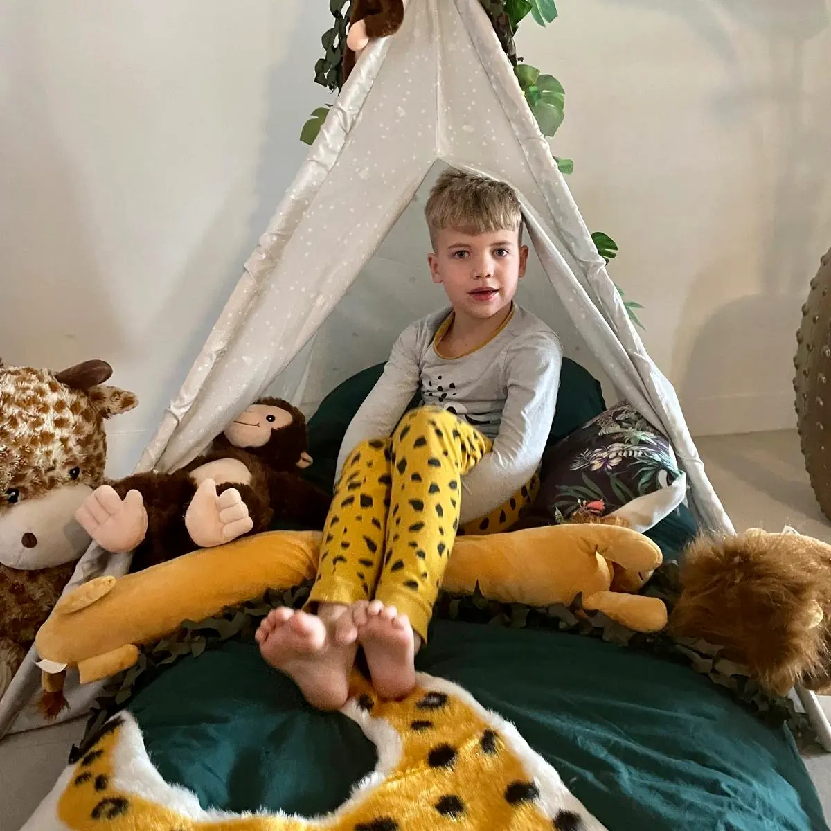 Jongen ontspant in zijn jungle tipi tussen de knuffeldieren
