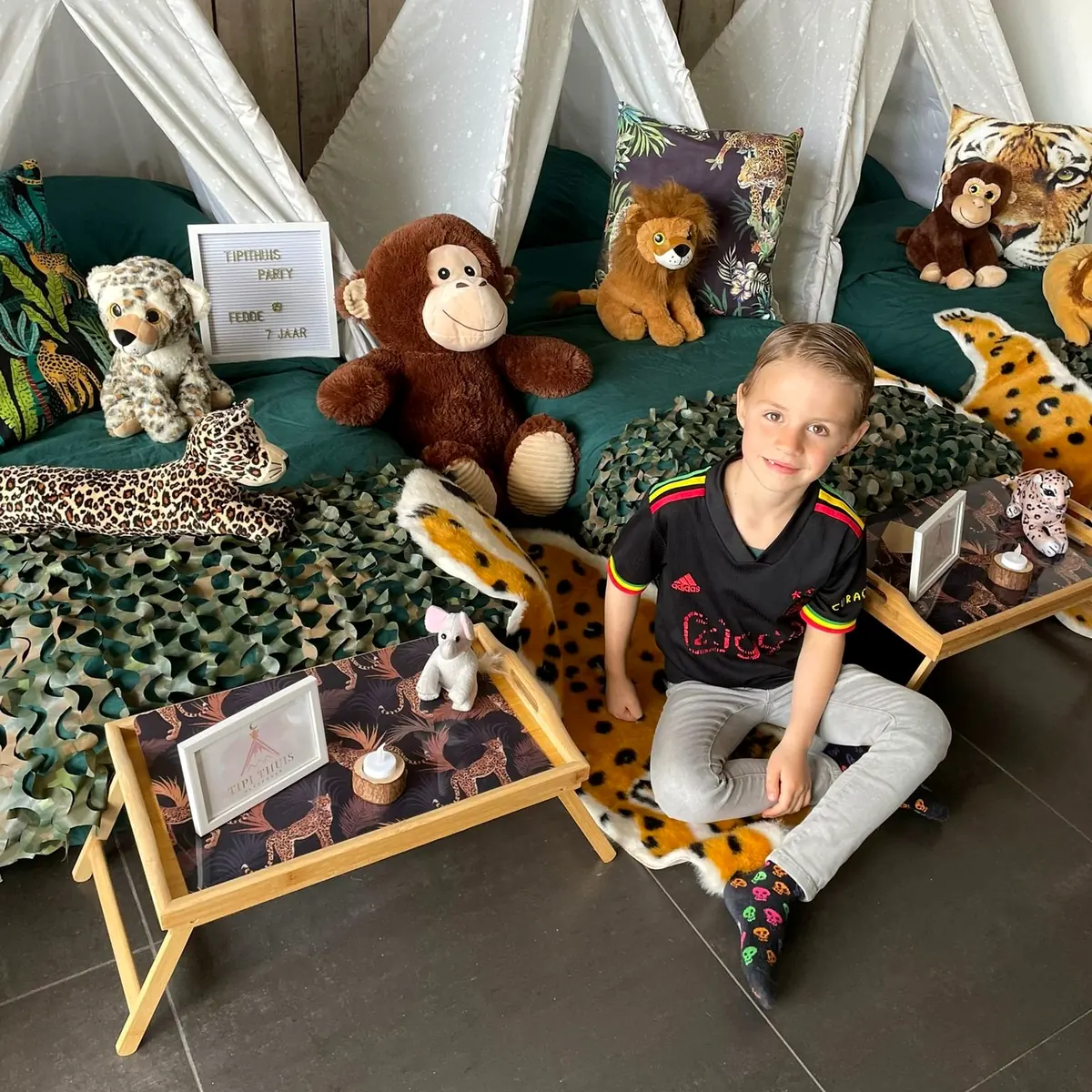 Jongen zit bij zijn jungle tipi met knuffelaap en ontbijtplankje