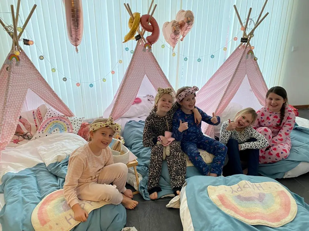 Kinderen in pyjama zitten samen voor de rainbow tipi’s