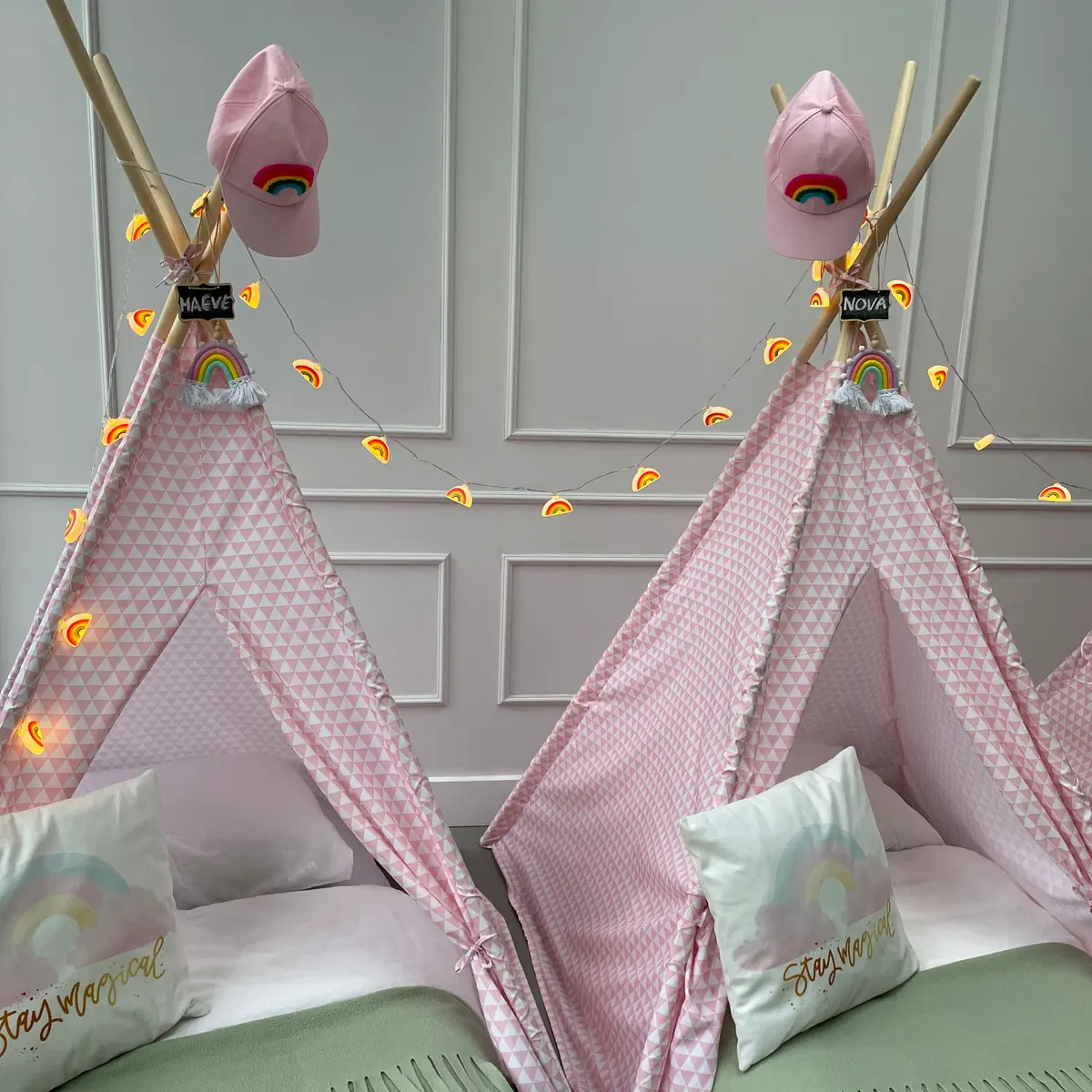 Rij roze rainbow tipi’s met lampjes en regenboogkussens