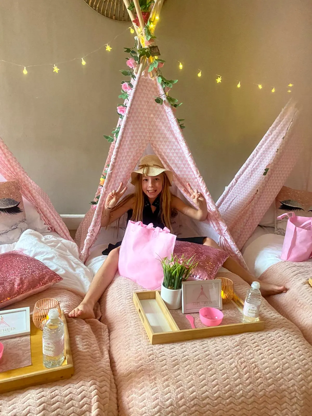 Meisje in een roze tipi met lampjes in het warme avondlicht